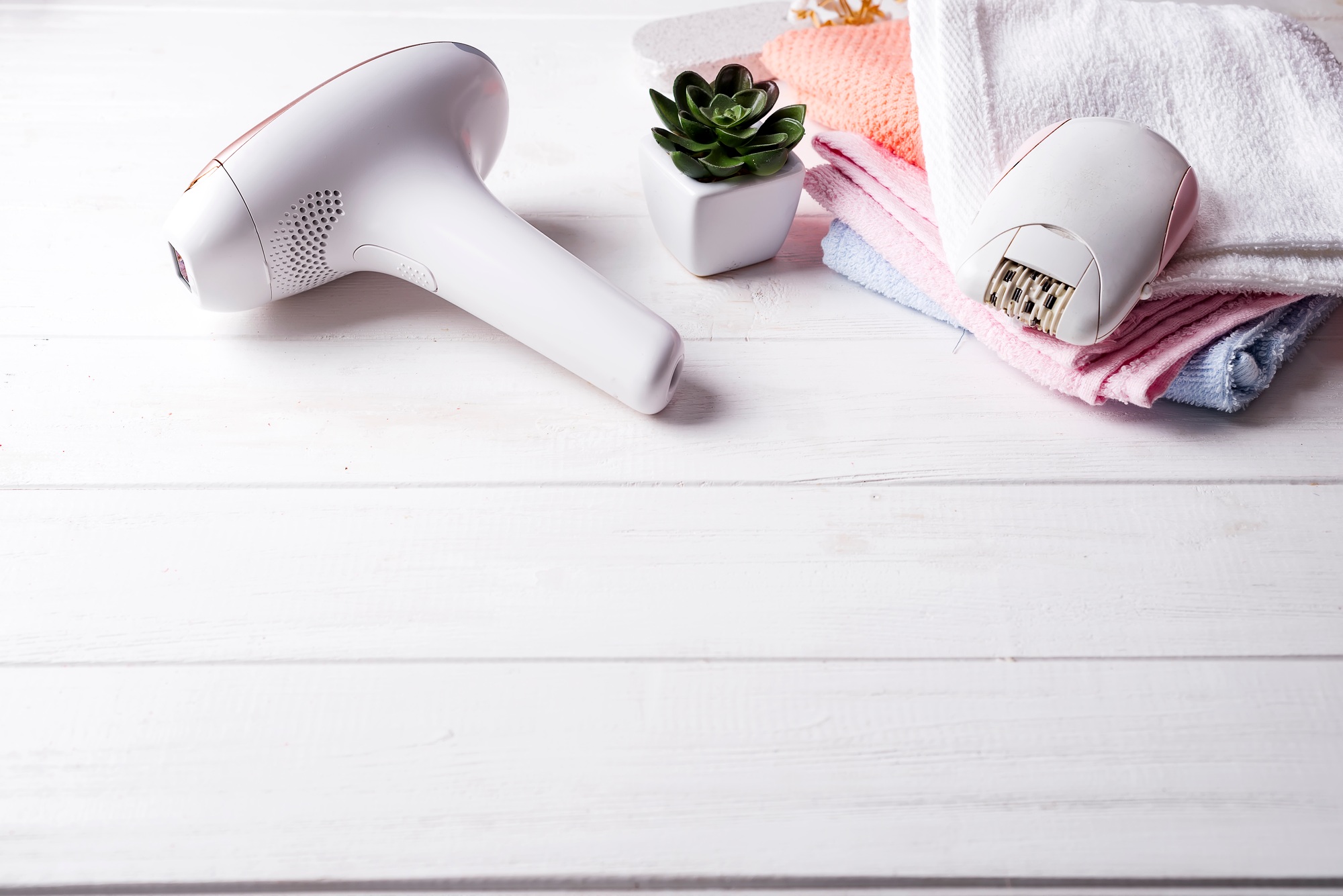 a hair removal device next to towels and a succulent